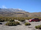 Jedeme chilským altiplanem pod čoudící sopkou Isluga (5550m), Chile