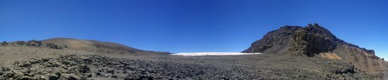 Kilimandžáro (5895m) - na hraně kráteru po vylezení Western Breach Route ve výšce 5750m. Nalevo se mírně zvedá vnitřní sopouch s nejvyšším místem Kibo Reusch Crater (5852m) a napravo je hrana kráteru s hlavním vrcholem Kilimandžára Kibo (5895m).