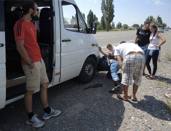 Improvizovaná oprava prasklé přední pneumatiky na krajnici u dálnice, Kyrgyzstán