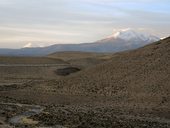 Čoudící sopka Guallatiri (6071m) a vzdálený vrcholek Parinacoty (6248m), Chile/Bolívie