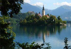 Bledské jezero a ostrůvkem Blejski otok s poutním kostelem Panny Marie, v pozadí hrad nad městem Bled.