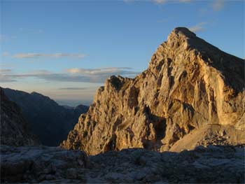 Zapadajícím sluncem nasvětlený Begunjski vrh (2461m) během sestupu.