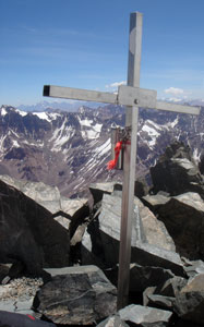 Vrcholový kříž na hoře Vallecitos (5550m). V dáli přímo za křížem je skyta hora Aconcagua (6962m).